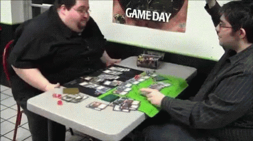 two men sit at a table playing a game