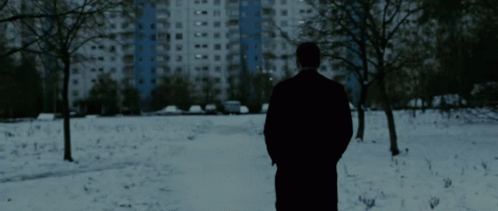 a person is standing in the snow in front of tall buildings
