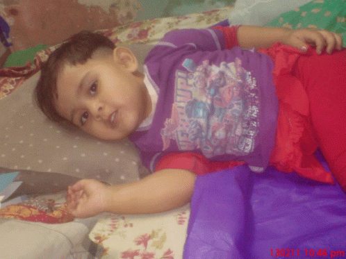 a child is lying on a bed wearing a red and purple shirt
