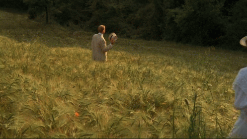 two people are standing in a field looking at an owl