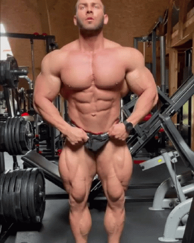 a male bodybuilding model standing at the gym posing