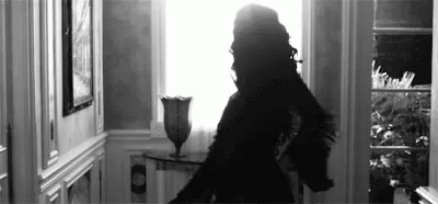 a person in a dress in a hallway with a light coming through the window