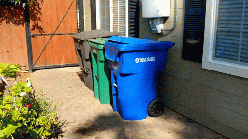 three bins are in the corner of a home driveway