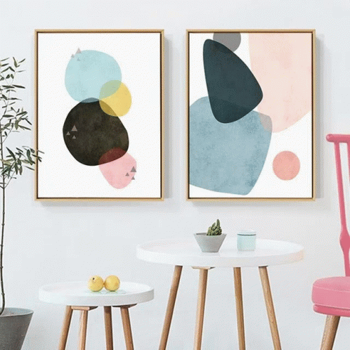 two paintings on wall above small tables and blue chairs