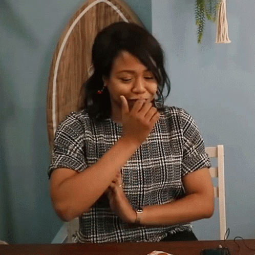 a woman laughing while her hands together behind her face