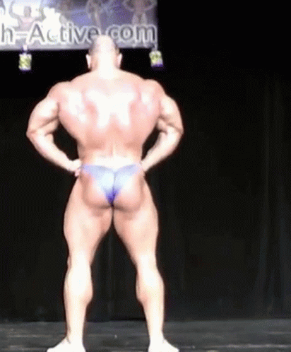 a bodybulding that is standing on the ground with his front  and his back turned