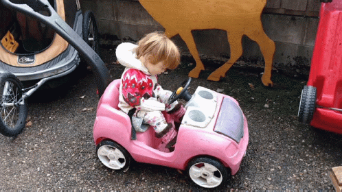 a small blue eyed child driving a toy car