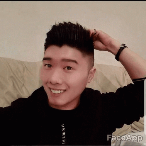 a young asian man with a short haircut smiles for the camera