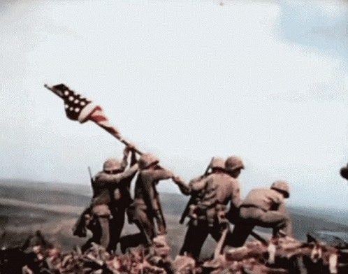 a group of soldiers holding a flag and raising it on a hill