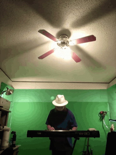 person with white hat playing keyboards in small room