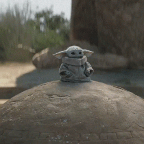 a baby yoda sitting on top of a metal ball