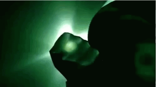 a dark image with a green glow on the wall and black hands