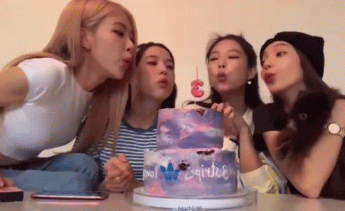 a group of women in front of a birthday cake