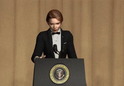 a woman wearing a suit and tie at a podium