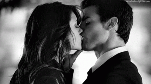 two people dressed in black, and white kissing each other