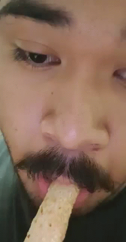 a man with a mustache and fake food in his mouth