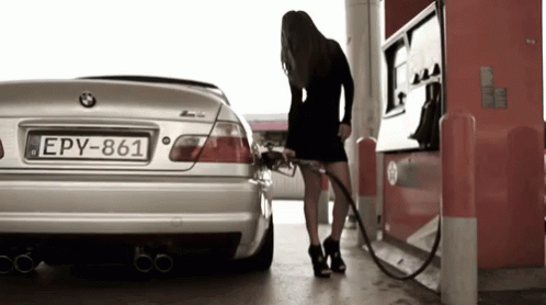 a woman is pumping petrol at a gas station
