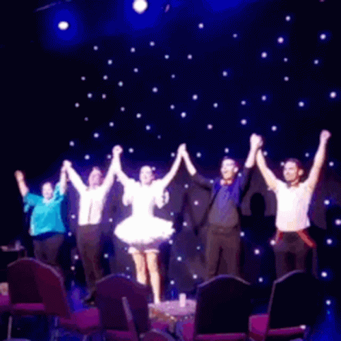 a group of people on stage with their hands in the air