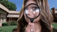 a magnifying glass reveals the face and head of a woman