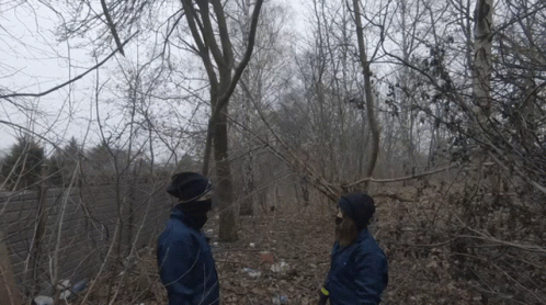 two men are in the woods while wearing jackets