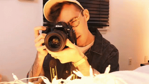 a man with glasses and a hat is taking a picture