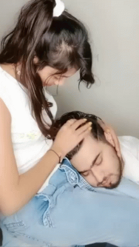 a girl sitting on a bed playing with a man head