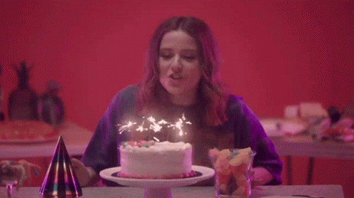 the woman has a birthday cake with lit candles