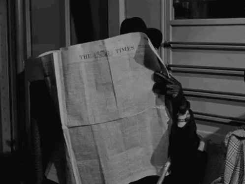 there is a man sitting down reading a newspaper