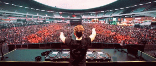 a person standing at a djs booth in front of a crowd of people