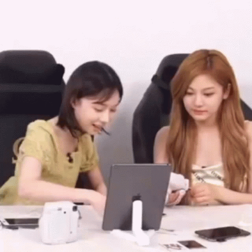 two young women are looking at a laptop together