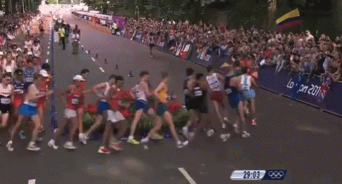 a crowd of runners make their way down the street