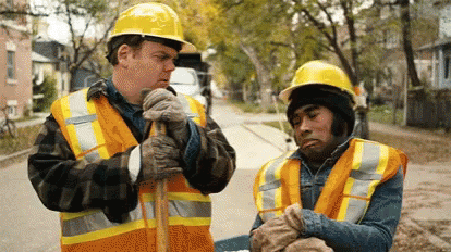 two men stand on the street with construction attire
