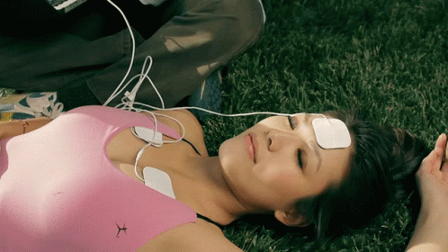 a person lying on the grass playing with headphones