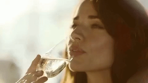a beautiful young woman holding a wine glass to her mouth