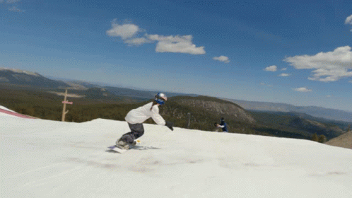 a person riding a snowboard down the side of a snow covered slope