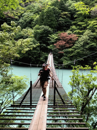 man walking across a bridge to cross the water