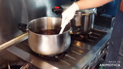 a person stirring blue liquid into pots on a stove