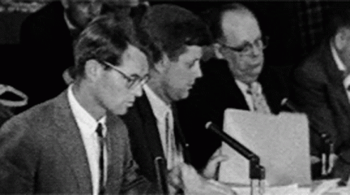three men sit at a table with papers and papers