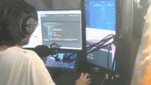 someone wearing headphones at a computer looking at several monitors
