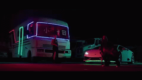 a truck with its lights on sitting in the street next to another bus