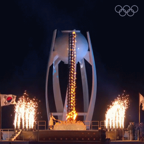 olympic torch lighters lit up during a night ceremony