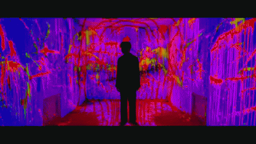 a man standing in a hallway with neon lights