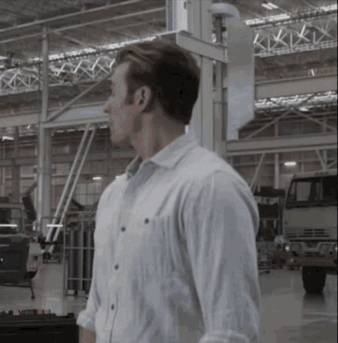 a man walking through an automobile factory with trucks