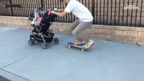 a child hing a stroller next to a man riding on a skateboard