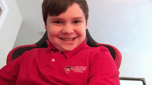 a little boy wearing a purple shirt smiling