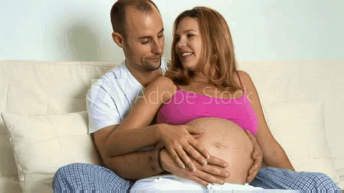 a pregnant couple emcing while sitting on the couch
