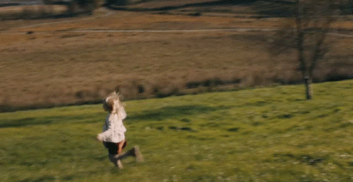 a girl running on top of a green field