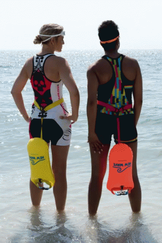 two male surfers dressed in colorful outfits stand at the waters edge