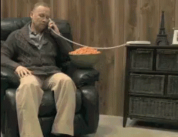 a man is sitting in a chair talking on a cell phone