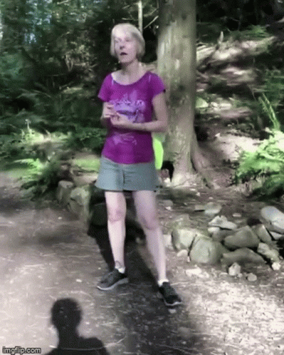 a woman walking down a path through the woods